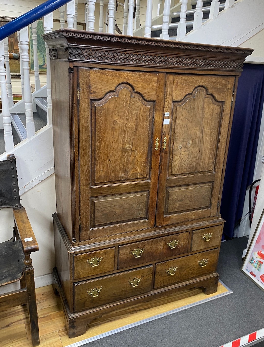 A mid 18th century panelled oak hanging cupboard on chest, fitted five small drawers, width 120cm, depth 53cm, height 185cm